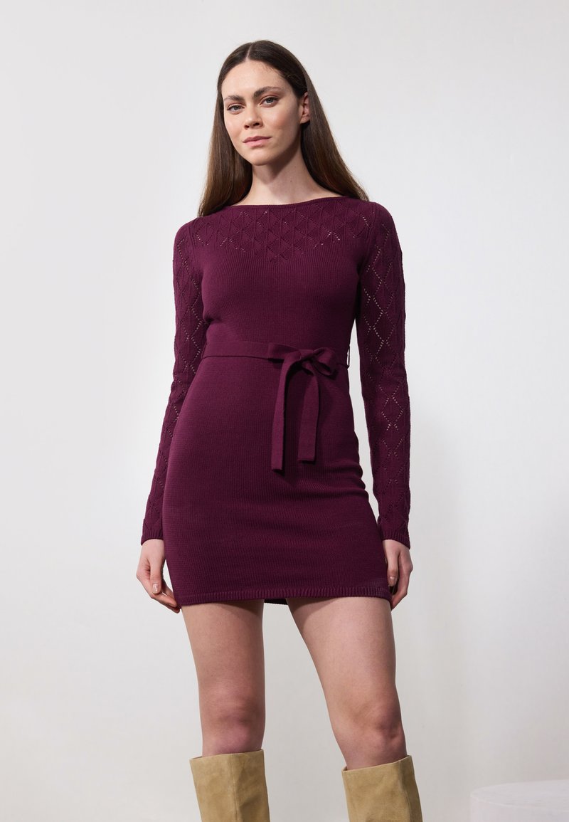 Sügavburgundi tooni kootud kleit pikkade teemantmustritega varrukatega, kitsas bodice ja sobiv vöö talje ümber. Sile tekstuur, põlve kõrgune pikkus.