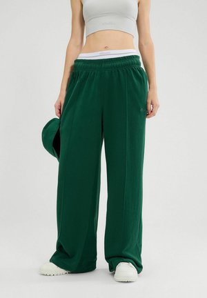 Groene, losse sweatpants met een elastische tailleband en zijzakken. Gemaakt van zachte stof, gecombineerd met een grijze crop top en sneakers.