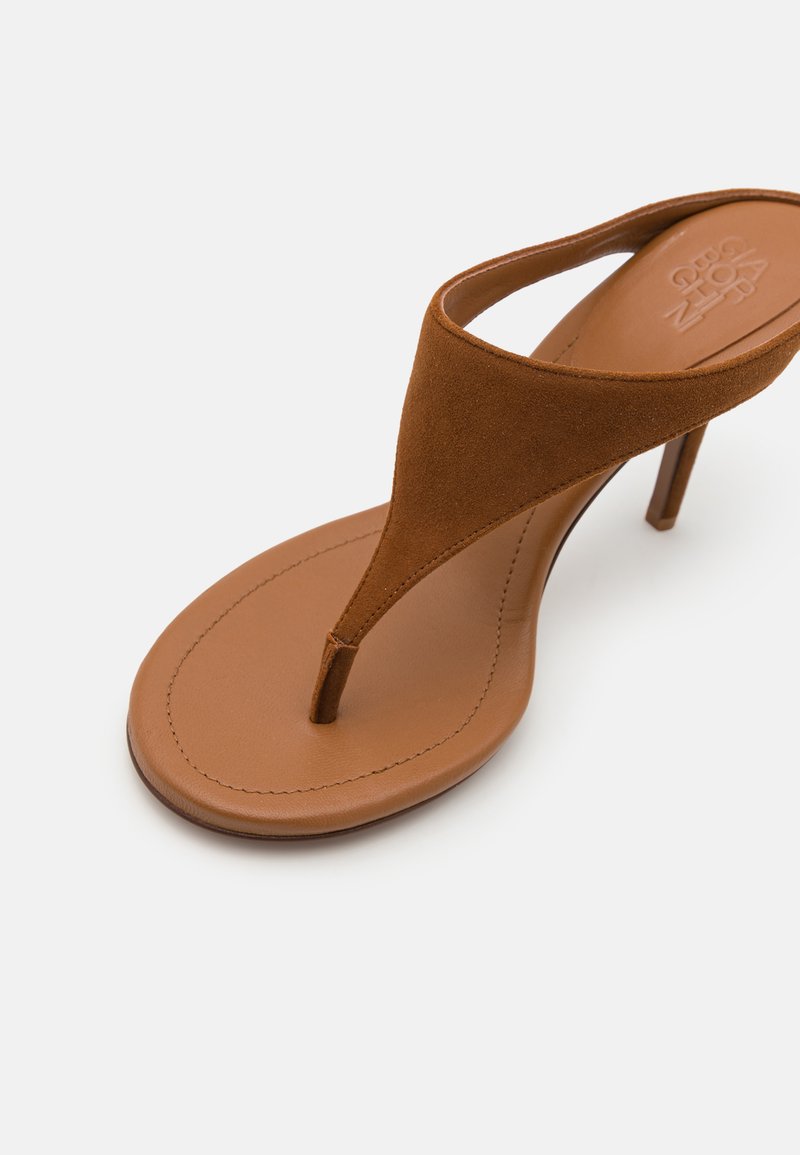 Sandale en cuir suédé marron avec un design élancé, un porte-orteil pointu et un haut talon aiguille. Semelle texturée pour une meilleure adhérence.