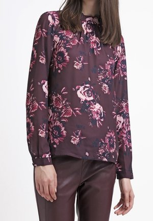 Pitkähihainen pusero burgundinvärisestä kankaasta, jossa on vaaleanpunaisen ja valkoisen sävyisiä kukka-aiheita, pyöreä pääntie ja rento leikkaus.