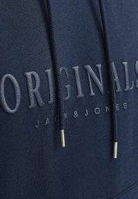 Marineblå hættebluse med struktureret "ORIGINALS" skrift, justerbare snore med metalspidser og en blød stofoverflade.