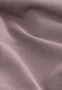 Kerge mauve kangas, millel on sile, veidi tekstuuriga pind, kus on peened, ühtlased kudumis Musterid ja õrnad voldid.