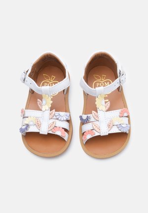 Sandales blanches pour tout-petit avec brides à la cheville ornées d'applications de fleurs et de feuilles rose, violette, jaune sur des semelles beige clair.
