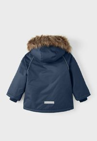 Námořnická modrá, zateplená bunda s kapucí lemovanou kožešinou. Obsahuje elastické manžety, detaily se zipem a reflexní akcent na zadní straně.