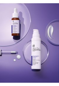 Flacon en verre brun avec pipette blanche, sérum de rétinol à côté d'un flacon à pompe blanc, d'un plat rond et de textures crémeuses sur un fond violet.