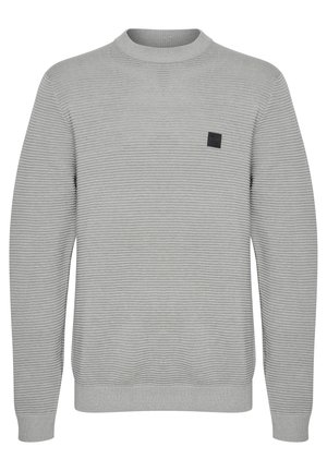 Svetlo sivi pulover z rebrastim vzorcem, okroglim izrezom in črnim kvadratnim logotipom na levi strani prsnega koša. Dolge rokave z rebrastimi manšetami.