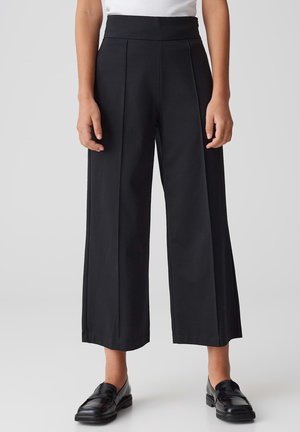 High-waisted black trousers with wide legs, featuring front pleats, smooth texture, and a clean waistband design. Classic, versatile style.