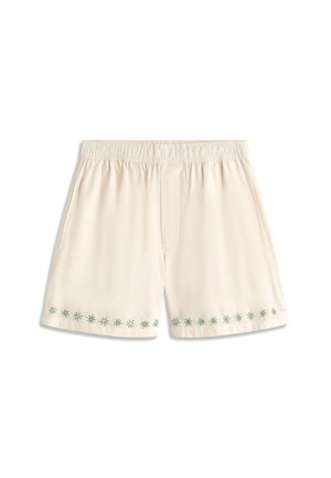 Shorts couleur crème avec taille élastique et broderie verte en forme d'étoile le long de l'ourlet inférieur.