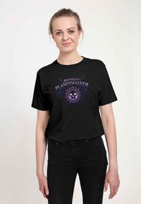 T-shirt in cotone nero con stampa grafica recante il testo "BIRTHDAY PLANESWALKER", design di teschio e accenti viola sul davanti.
