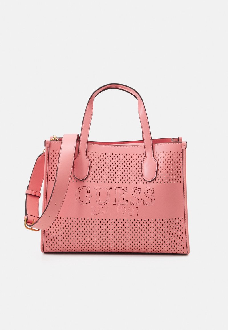 Sac cabas en cuir rose avec un design perforé et un logo embossé "GUESS EST. 1981", doté de deux poignées et d'une bandoulière réglable.
