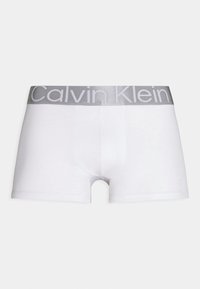 Bijele bokserice s glatkim materijalom, prilagođenim dizajnom i srebrnim pojasom s "Calvin Klein" logotipom.