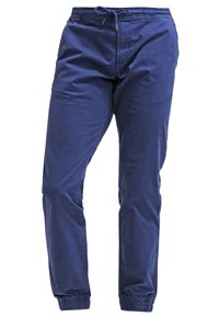 Námořnické modré bavlněné kalhoty s nápletem v pase, elastickými manžetami a postranními kapsami. Hladká textura s volným střihem.