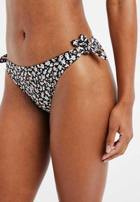 Kvetinové spodné bikiny v čiernej farbe, s malým kvetinovým vzorom v bielych a broskyňových akcentoch. Na bokoch majú detaily v podobe mašličiek.