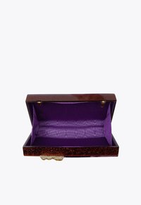 Czerwona kopertówka z brokatem i fioletową, materiałową podszewką. Posiada zawiasowe zamknięcie i złote okucia, prezentując prostokątny kształt i gładkie krawędzie.