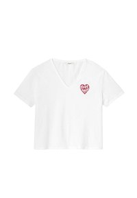 T-shirt en coton blanc avec un col en V, des manches courtes et un graphique en forme de cœur rouge avec le texte "More Amor" sur la poitrine gauche. Texture douce.