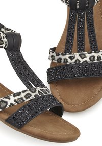 Zwarte sandalen met gestructureerde banden, voorzien van een luipaardprint en met strass accenten op de bovenkant. Zacht, bruin gezakt voetbed.