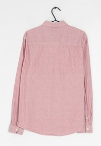 Chemise à manches longues en lin rose clair, dotée d'un col classique, de fermetures à boutons aux poignets et d'un ourlet arrondi avec une texture subtile.