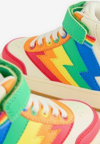 Šarene visoke tenisice s vibrantnim cik-cak uzorcima u narančastoj, žutoj, zelenoj, plavoj i crvenoj boji na krem osnovi s bijelim vezicama.