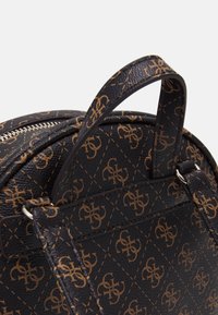 Musta nahkareppu, jossa on kultainen monogrammikuosi, pyöreä muoto, yläkahva ja hopeinen vetoketju. Rakeinen pinta.