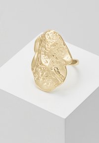 Gouden ring met een organisch, gestructureerd oppervlak en een onregelmatige vorm, voorzien van een gepolijste afwerking en een eenvoudige band.