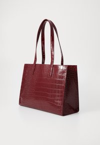 Sac cabas bordeaux à relief crocodile avec une finition brillante, doté de deux longues poignées et d'une forme rectangulaire structurée.