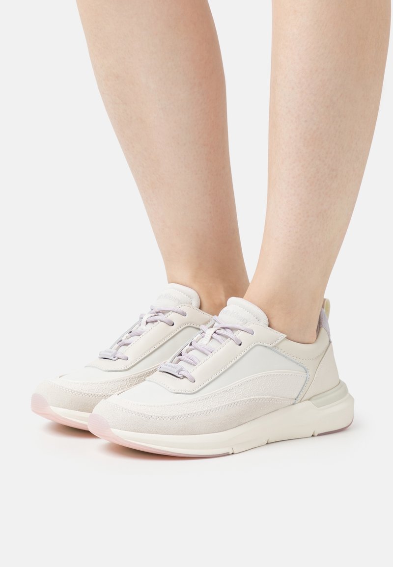 Scarpe da ginnastica chiare caratterizzate da un mix di pelle liscia e camoscio, con lacci e un sottile accento decorativo sul lato.