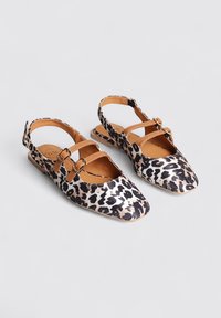 Zapatos planos de estampado de leopardo con punta afilada, detalles en color marrón claro y dos correas ajustables con hebilla. Presenta una textura suave y un diseño con talón abierto.