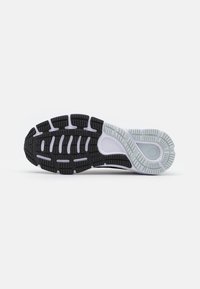 Semelle de sneaker en noir et blanc avec des motifs de semelle prononcés, présentant des rainures et des textures pour l'adhérence et la flexibilité. Design de talon rond inclus.