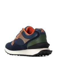 Zapatilla deportiva con una parte superior de gamuza azul marino, acentos en beige y verde, forro naranja y suela blanca con una suela exterior de goma negra texturizada.