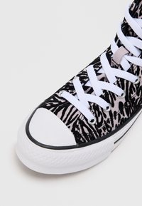 Melnbaltas zebras raksts sneaker ar auduma augšpusi, gumijas purngaliem, baltām šņorēm un strukturētu baltu zoli.