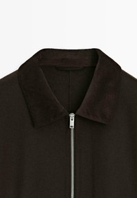 Giacca nera con colletto in velluto a coste e zip argentata. Texture morbida con un design classico.