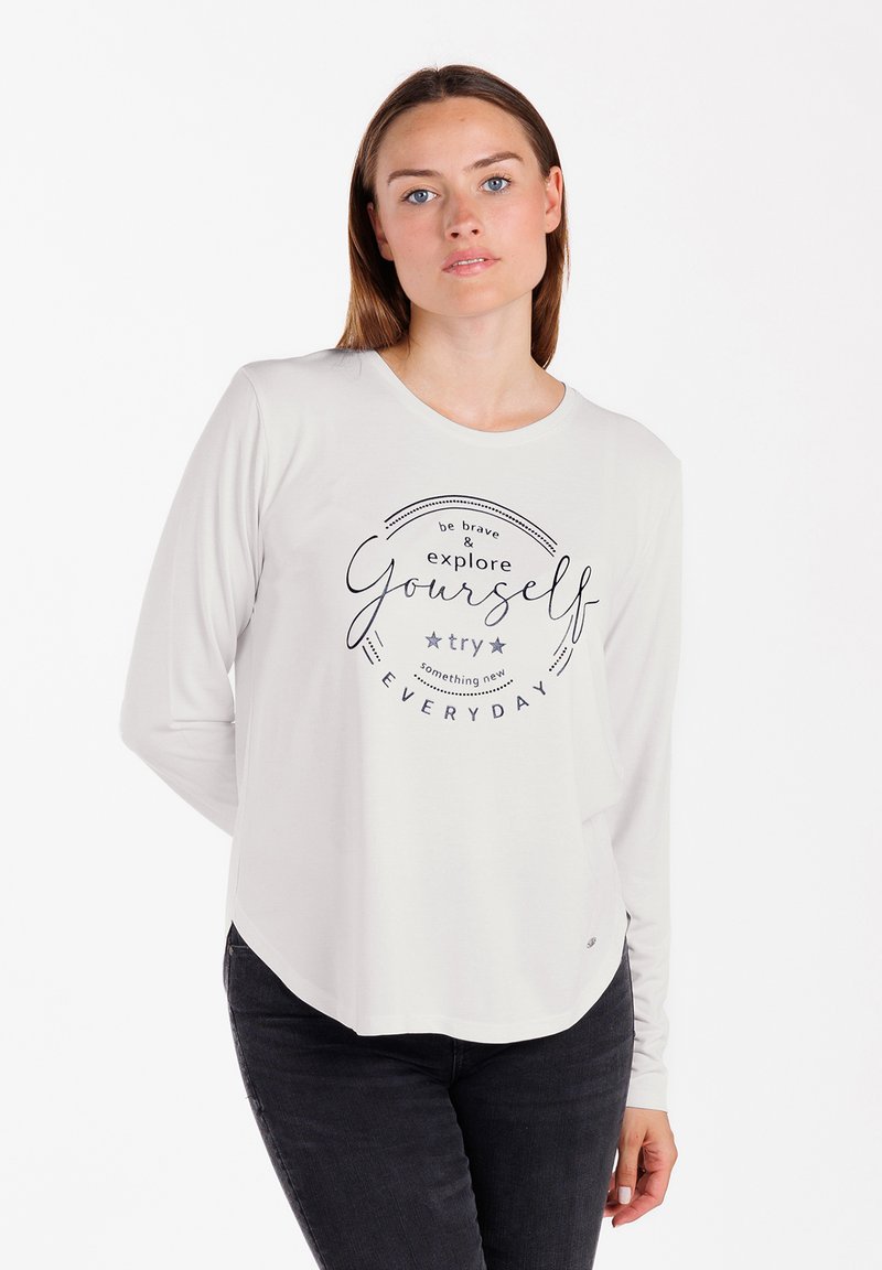 Langärmliges, hellgraues Shirt mit Rundhalsausschnitt und einem bedruckten Spruch: "sei mutig & erkunde dich selbst, versuche jeden TAG etwas Neues."