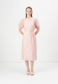 Klänning i pink med puffärmar, insvängd midja, längd till mitten av vaden, texturerad tyg och delikat blommönsterbroderi. Inkluderar ett matchande bälte.