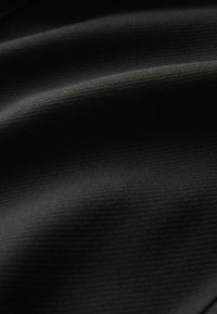 Sort stof med en glat, let tekstureret overflade og subtile bølger, der fremhæver dets bløde, fleksible materiale og jævne farve.