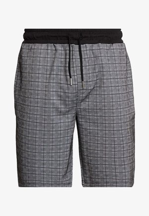 Shorts à carreaux noirs et blancs avec une taille élastique noire et un cordon de serrage noir aux extrémités argentées.