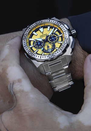 Orologio in acciaio inossidabile argentato con un grande quadrante giallo, quadranti secondari neri, dettagli argentati e bracciale a maglie.