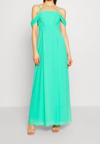 Pitkän mintunvihreän maksimekon, joka on valmistettu kevyestä kankaasta. Mekossa on olkaimeton malli, istuva vyötärö ja löysä helma.