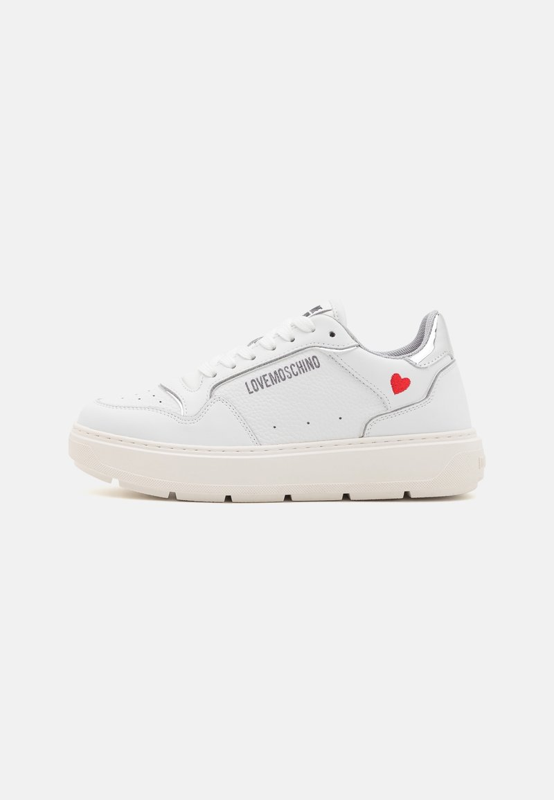 White leather sneaker with a textured finish, featuring a grey logo and small red heart detail. Thick beige rubber sole. Laced design.