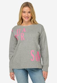 Grå sweatshirt med stora rosa bokstäver "S" och "AUR" i en lekfull design. Tillverkad av mjukt, strukturerat tyg med långa ärmar.