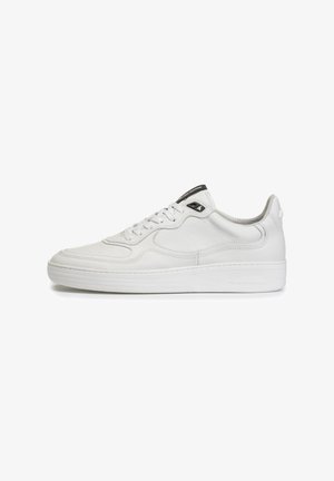 Witte leren sneaker met een gladde textuur, ronde neus, zichtbare stiksels en een zwart logo accent op de tong. Platte witte rubberen zool.