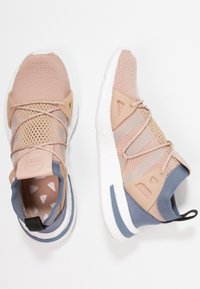 Scarpe da corsa rosa chiaro con tomaia in mesh traspirante, dettagli in gomma e suola testurizzata con particolare posteriore blu e intersuola bianca.