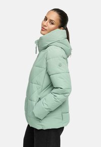 Jasnozielona kurtka puchowa z wysokim kołnierzem, diagonalnym przeszyciem, zamykanymi na zamek kieszeniami i delikatnym połyskiem. Posiada logo na rękawie.