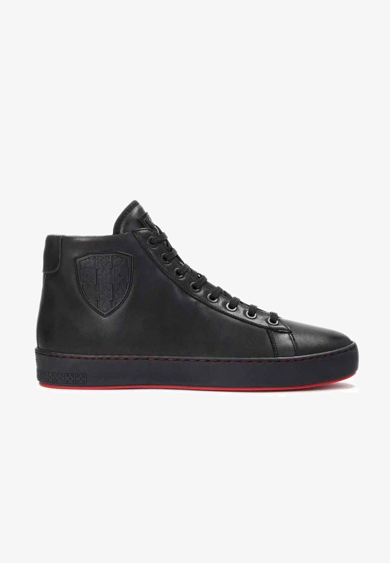 Adidași negri din piele cu gât înalt, cu un logo texturat în formă de scut, vârf rotund, ochi metalici și o talpă contrastantă roșie.