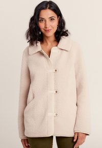 Giacca in pile beige chiaro con colletto, zip anteriore e bottoni a toggle. Presenta tasche laterali e una finitura morbida e texture.