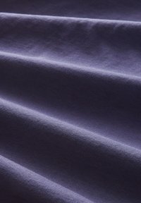 Mörklila bomullstyg med en mjuk textur och subtila, horisontella veck. Ingen tydlig mönster eller detaljer synliga.