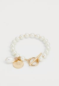 Pulsera de perlas con perlas redondas blancas, cierre de palanca en tono dorado y un charm decorativo con iniciales y un acento rosa.