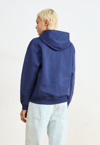 Sweatshirt com capuz azul-marinho, feito de tecido macio, apresentando um corte confortável, punhos canelados e um capuz grande para maior aquecimento.