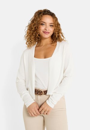Cardigan blanco con diseño de abertura frontal, mangas largas y textura suave, combinado con una blusa blanca y pantalones beige, acentuado por un cinturón de estampado de leopardo.