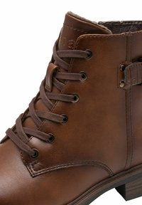 Brown leather ankle boot featuring brown laces, metal eyelets, and a textured accent near the heel. Sturdy sole and stitched detailing.