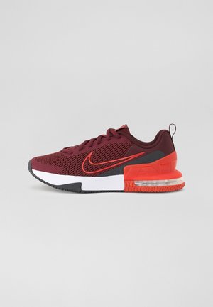 Bordowo-pomarańczowy sneaker Nike z siateczkową cholewką, widoczną poduszką powietrzną w podeszwie, czarnymi akcentami i białą śródpodeszwą na szarym tle.